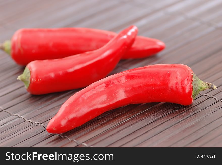 Close-up of red chillies on a wooden place mat. Close-up of red chillies on a wooden place mat.