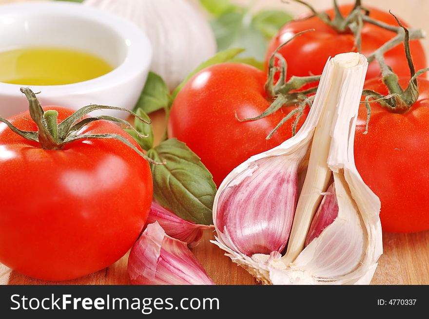 Close-up of garlic, tomatoes, basil and olive oil in a white dish. Close-up of garlic, tomatoes, basil and olive oil in a white dish.