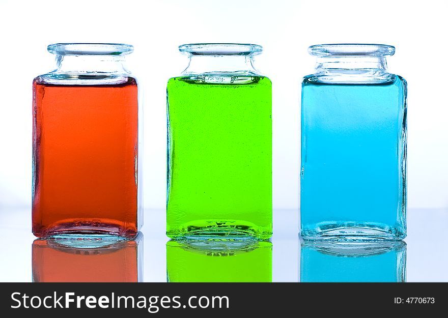 Three glass bottles containing different color liquids: reed, green, blue. Three glass bottles containing different color liquids: reed, green, blue