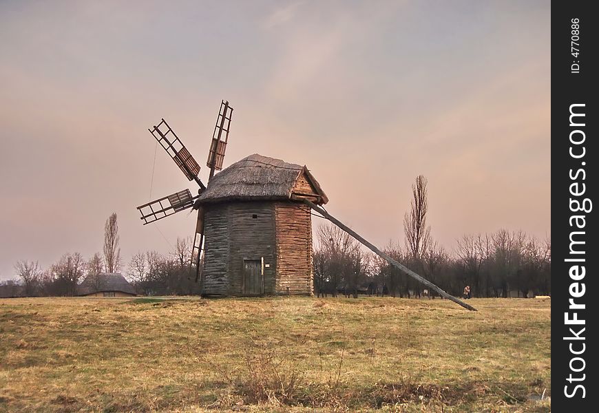 Countryside. At the edge of meadows, an old wooden windmill. The sky, trees and shrubs. Countryside. At the edge of meadows, an old wooden windmill. The sky, trees and shrubs