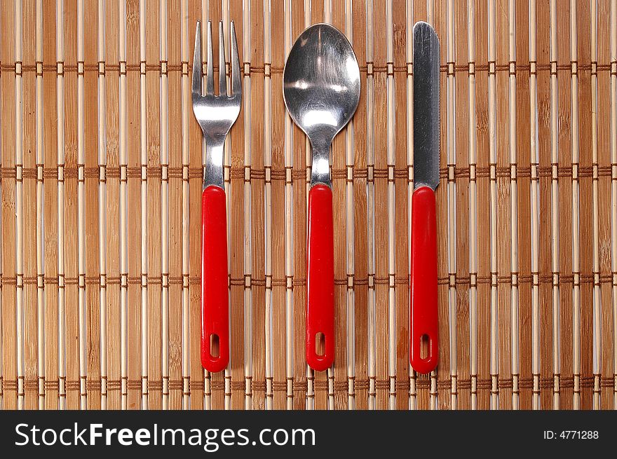 Set of spoon, fork and knife on bamboo background