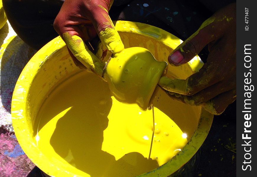 A man coloring pots into yellow color. A man coloring pots into yellow color