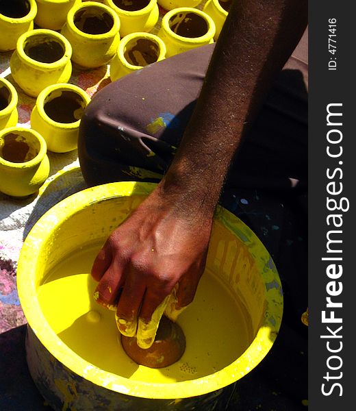A man coloring yellow colored pots. A man coloring yellow colored pots