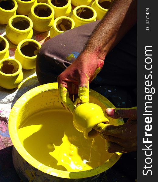 A man working and coloring yellow colored pots. A man working and coloring yellow colored pots