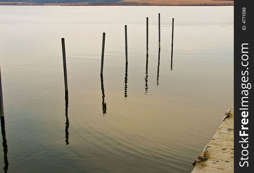Poles sticking out of lake near pier. Poles sticking out of lake near pier