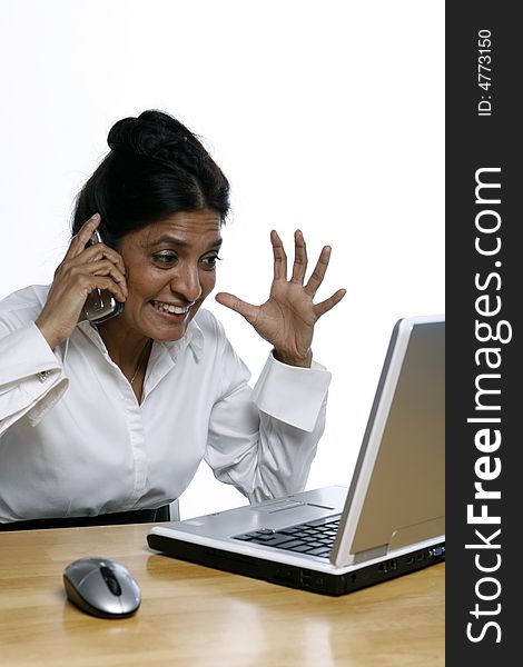 Vertical shot of an Indian woman at her laptop while on the phone. Vertical shot of an Indian woman at her laptop while on the phone