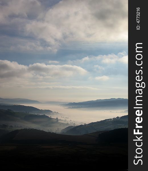 Mist in the valley with hills and cloudy sky