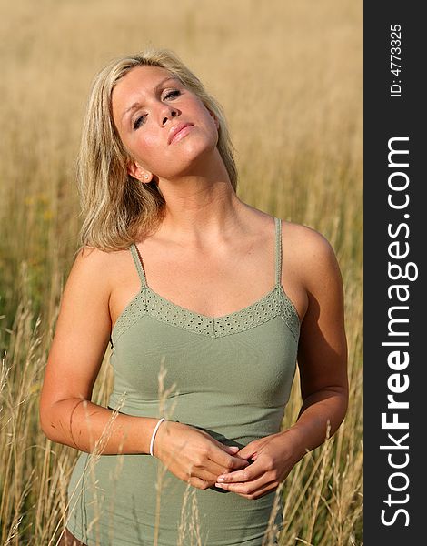 Beautiful blond woman standing in a high grass. Beautiful blond woman standing in a high grass
