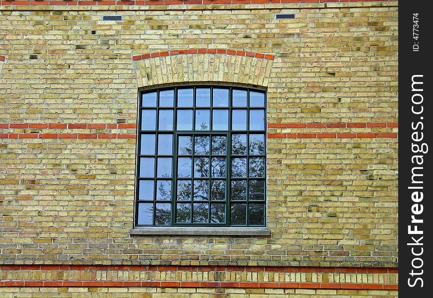 Yellow earth colors bricks wall and a window with reflection