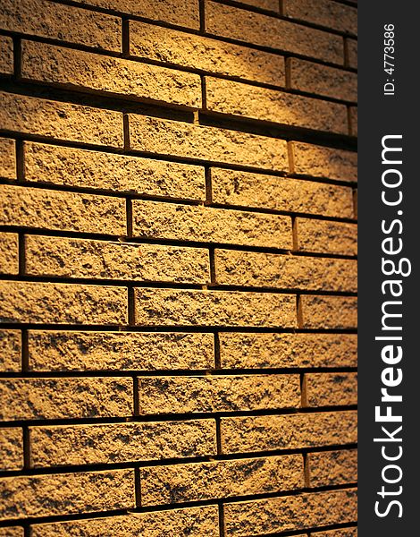 A wall of yellow bricks lit from the top with a spot light.