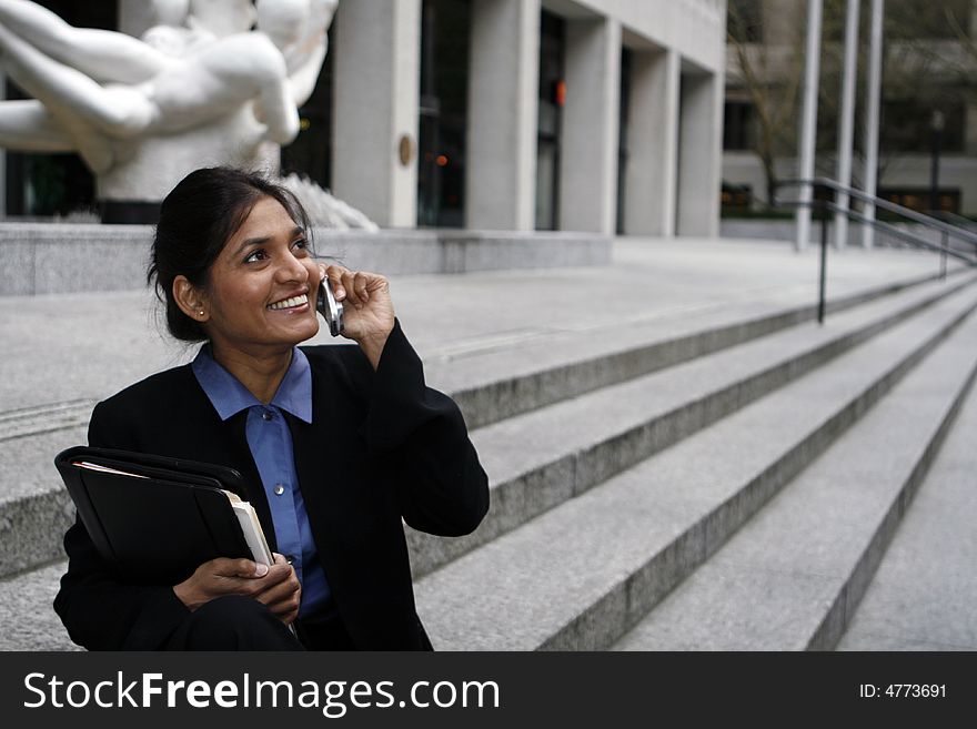 Exceutive Indian woman talking on a cellphone dressed in a black suit. Exceutive Indian woman talking on a cellphone dressed in a black suit.