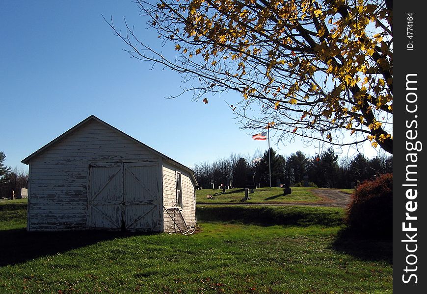 White Shed by Cemetery under a Blue Sky