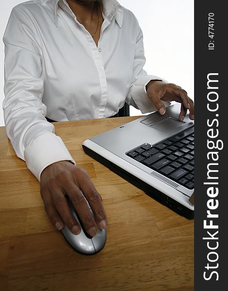 Vertical shot of an Indian woman working on a laptop while sitting at a wooden desk. Vertical shot of an Indian woman working on a laptop while sitting at a wooden desk