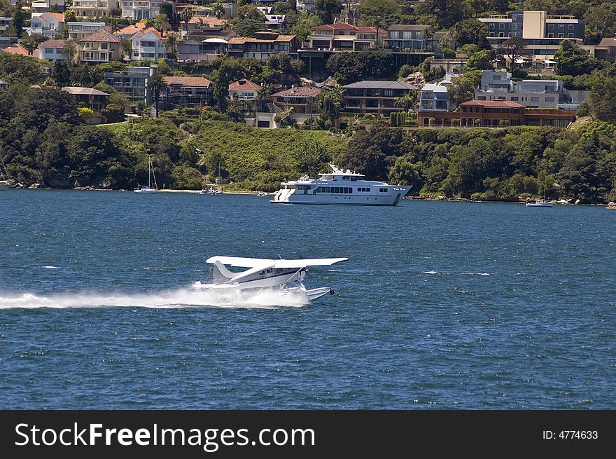 Small aircraft landing on water in sydney harbor australia and yacht and buildings in background. Small aircraft landing on water in sydney harbor australia and yacht and buildings in background