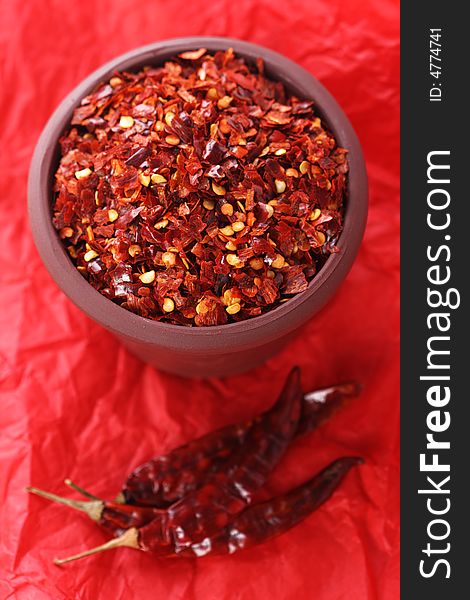 Hot Red Chilli Chillies crushed pepper in teracotta pot on red Background, Shallow DOF. Hot Red Chilli Chillies crushed pepper in teracotta pot on red Background, Shallow DOF