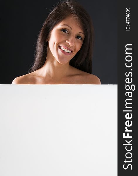 A beautiful and attractive girl holding a billboard. Ready to add your own text. Copy-space on a sign or poster. Young girl holding a sign, advertisement or poster. The concept of this picture is: copy-space on a white board or advertising. A beautiful and attractive girl holding a billboard. Ready to add your own text. Copy-space on a sign or poster. Young girl holding a sign, advertisement or poster. The concept of this picture is: copy-space on a white board or advertising.