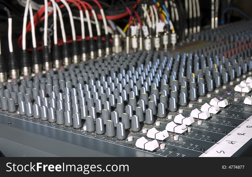 Large audio mixing board at a concert used for live mixing and balancing of various instruments and singers, showing the depth of field