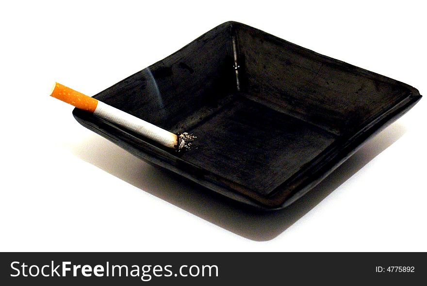 Shot of a cigarette lit in an ashtray. Shot of a cigarette lit in an ashtray