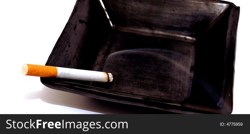 Shot of a cigarette lit in an ashtray. Shot of a cigarette lit in an ashtray
