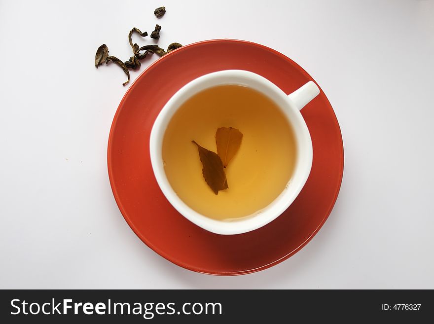 Green tea is in a cup, on a red saucer, isolated. Green tea is in a cup, on a red saucer, isolated