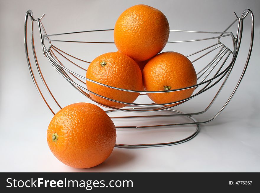 Four oranges in a vase made of steel twigs, isolated. Four oranges in a vase made of steel twigs, isolated