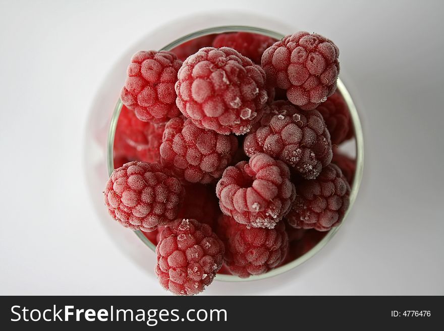 Raspberries with a hoarfrost, in glass tableware on white