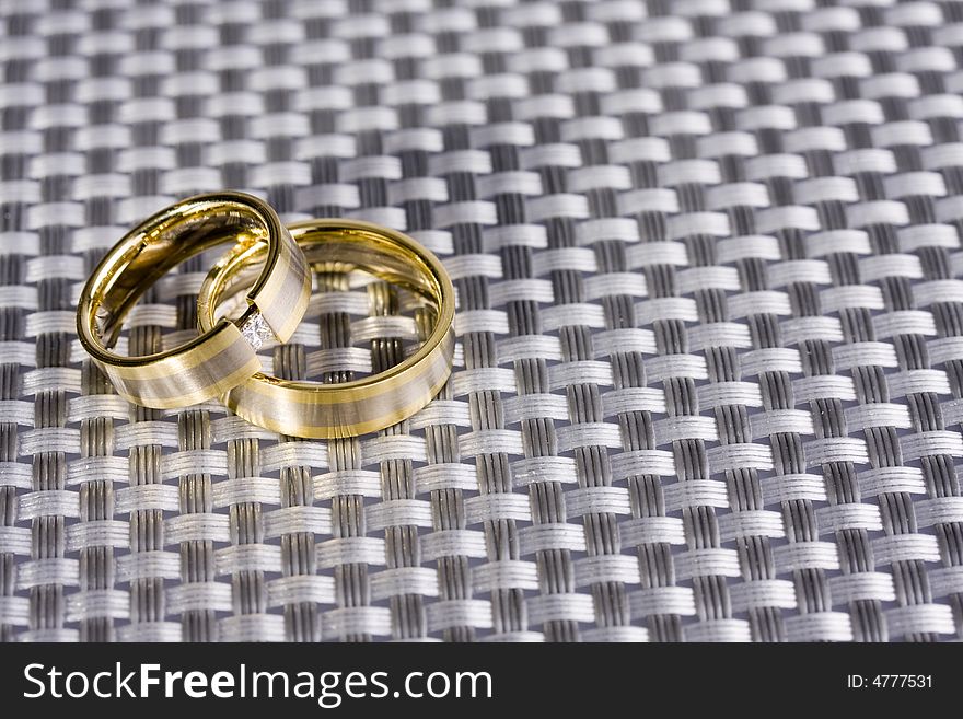 Golden rings for wedding presented on a silver structered backround