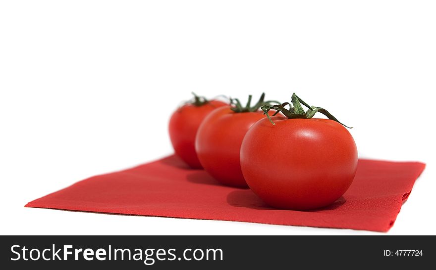 A row of red tomatoes lying on the red napkin.