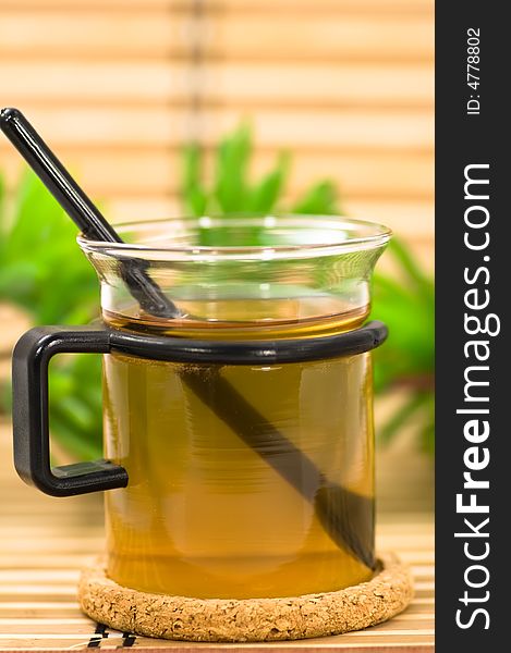 A cup of fresh tea and green plants on bamboo. A cup of fresh tea and green plants on bamboo