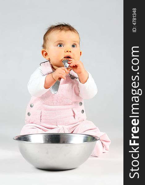 Small baby is sitting with bowl and spoon