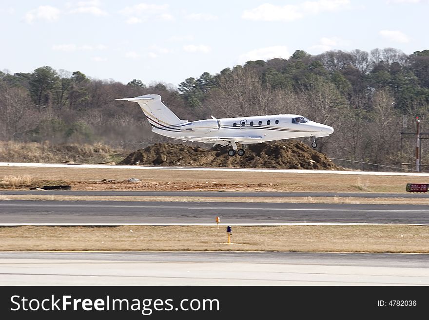 A white private airplane landing at a small regional airport. A white private airplane landing at a small regional airport