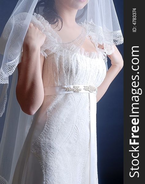 Bride standing in wedding dress at black background