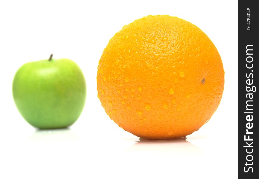 The ripe juicy apple covered by drops of water. Behind of a orange the green apple. Isolation on white, shallow DOF. The ripe juicy apple covered by drops of water. Behind of a orange the green apple. Isolation on white, shallow DOF.