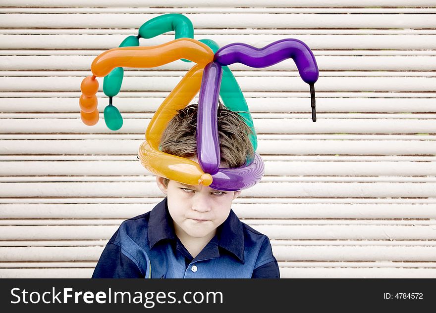 Young boy wearing a balloon hat with an angry face. Young boy wearing a balloon hat with an angry face