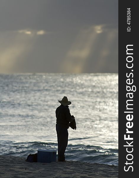 The man is fishing at the beach. The man is fishing at the beach