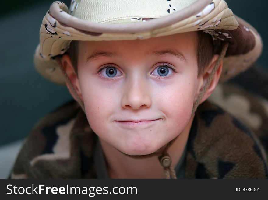 A smiling boy in the fatigues hat