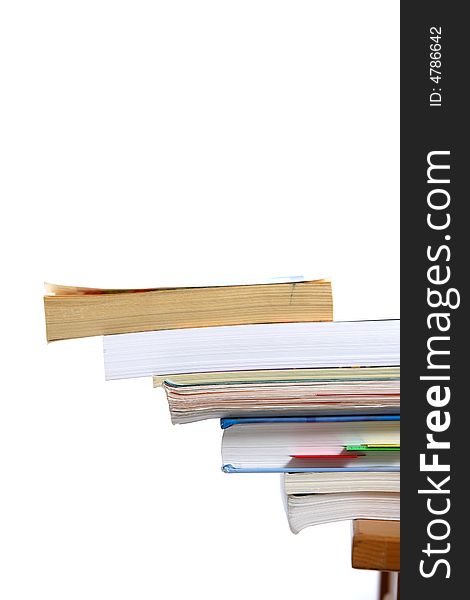 A stack of books sitting on the corner of a desk