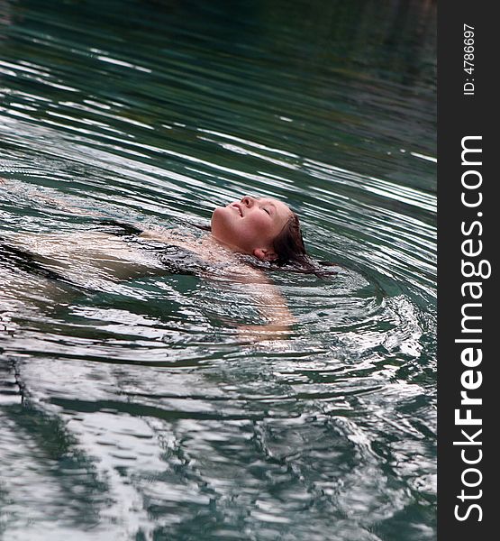 Woman floating in the water with her eyes closed.