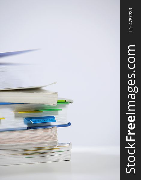 A stack of books sitting on the corner of a desk