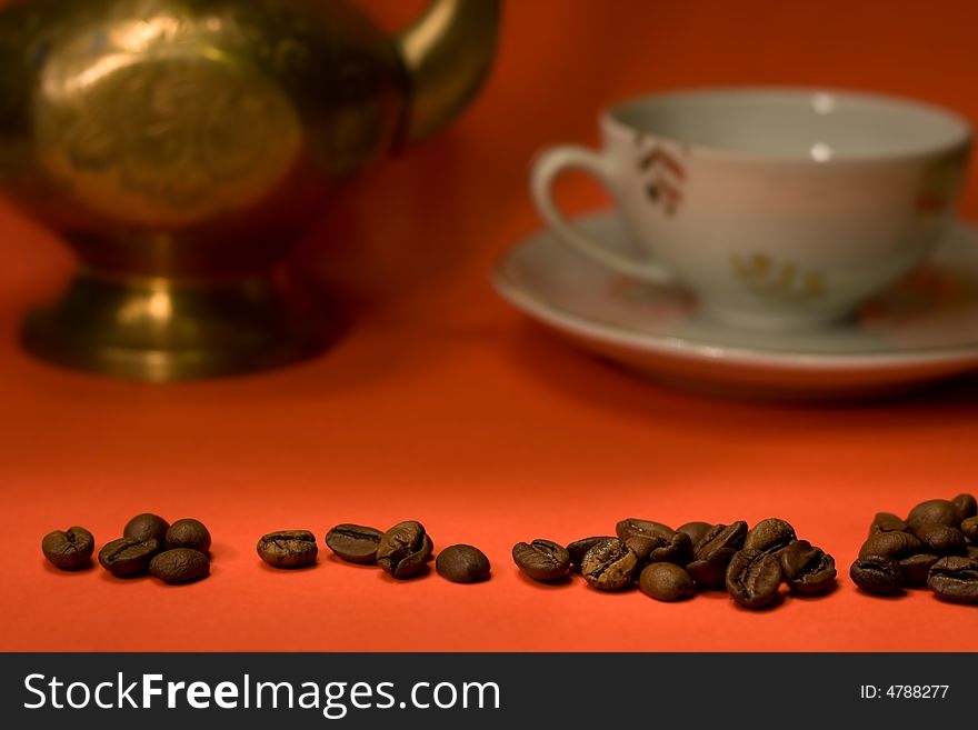 Coffee grains on red background with cup and pot