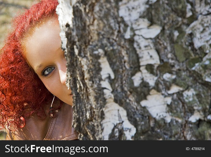 Beautiful young women hidden behind tree