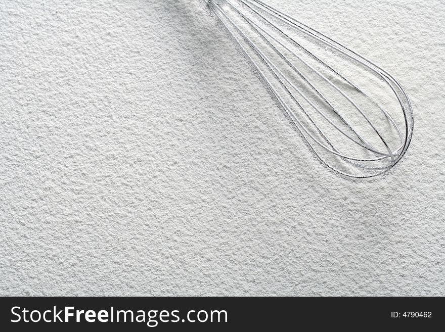 Wire whisk on flour, background