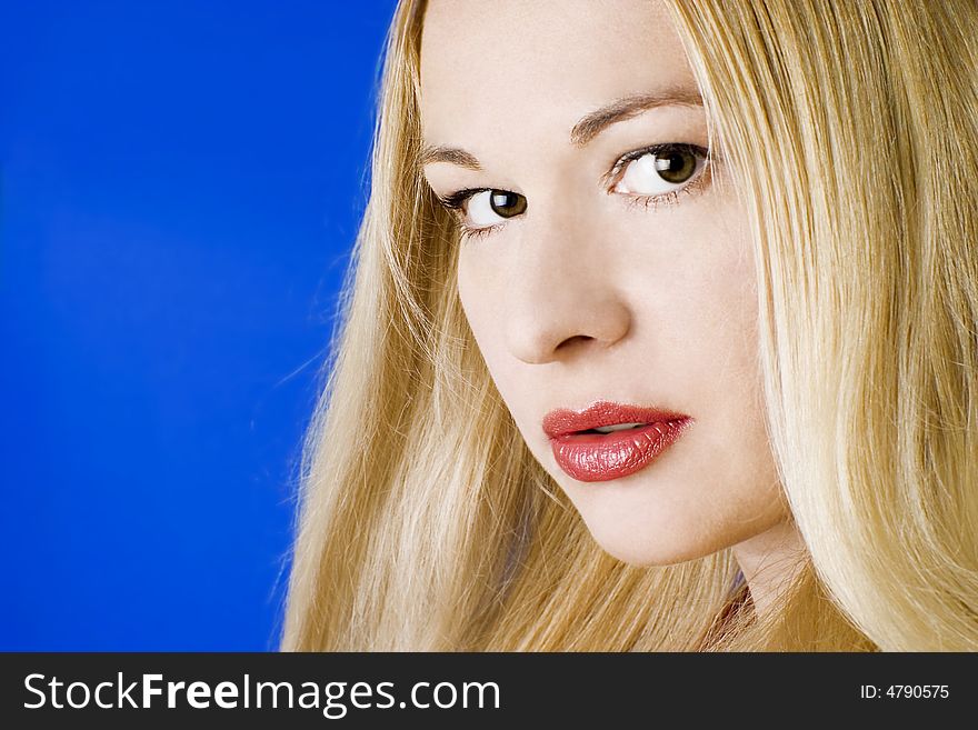 Beautiful young blonde woman with red lips. Blue background.
