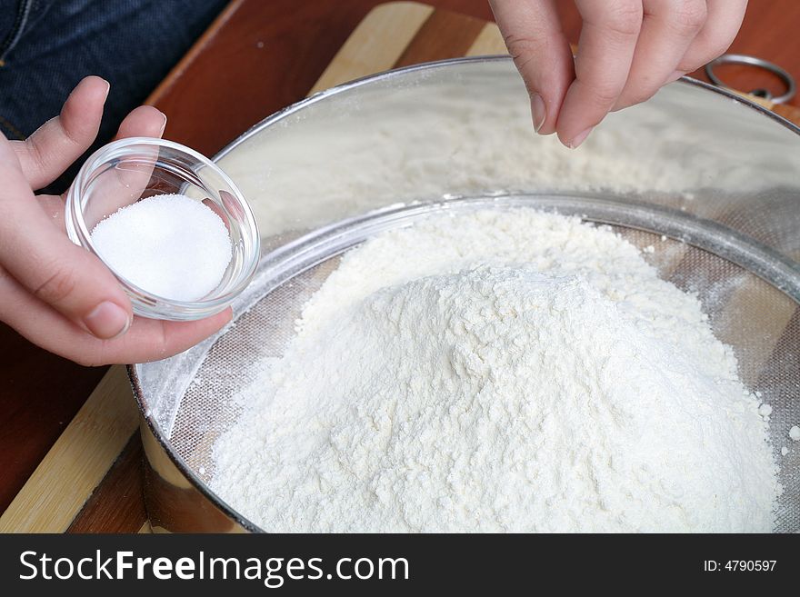 Sifting a flour on wooden board, background