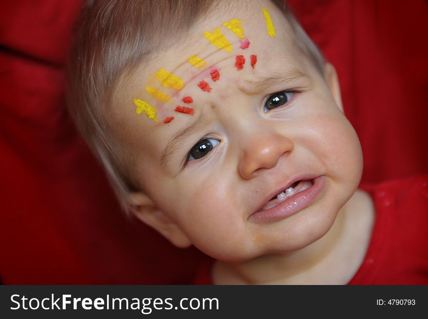 Young boy with painted forehead and sad face