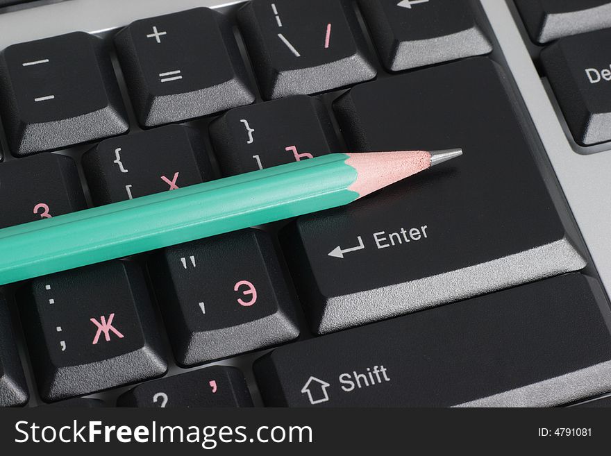 Computer keyboard and green pencil