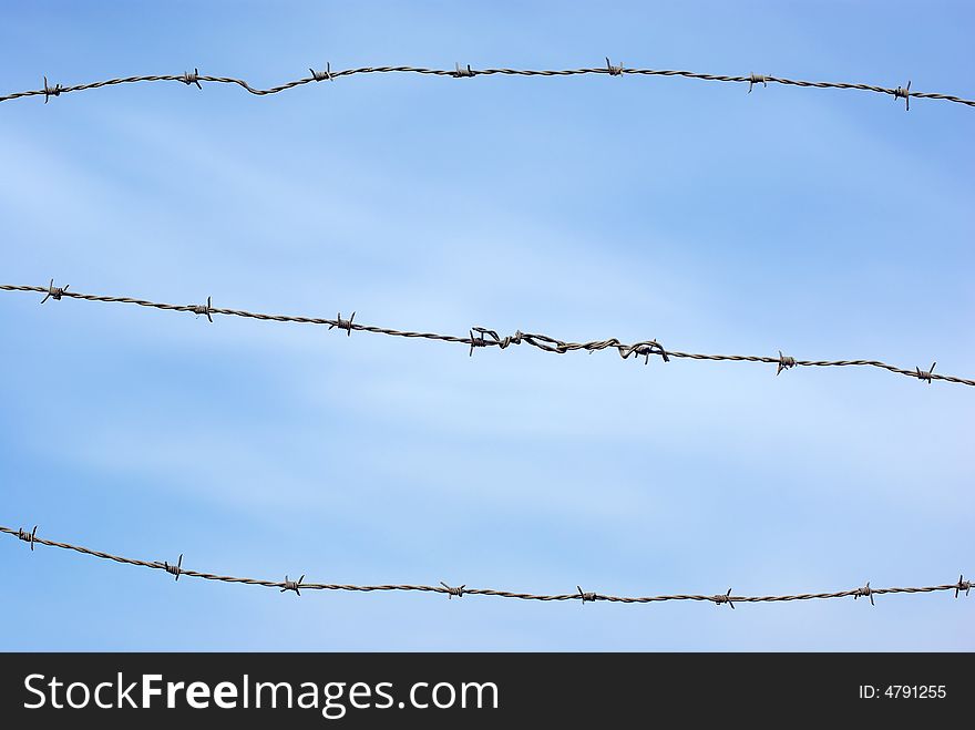 Barbed wire on blue sky.