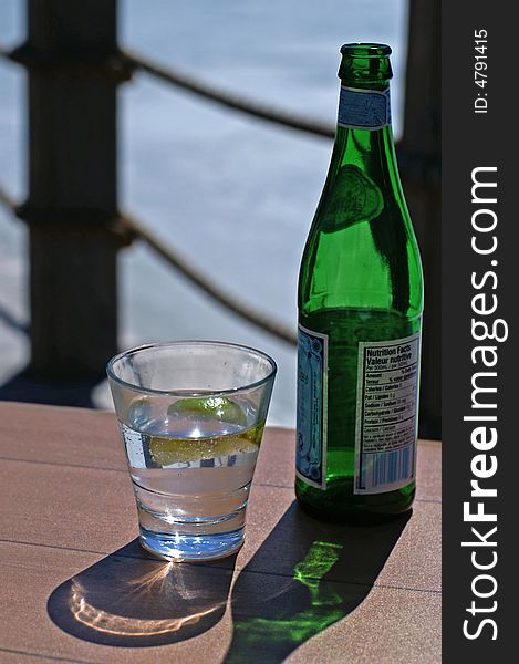 A refreshing glass of bottled water on a table by the dock. A refreshing glass of bottled water on a table by the dock