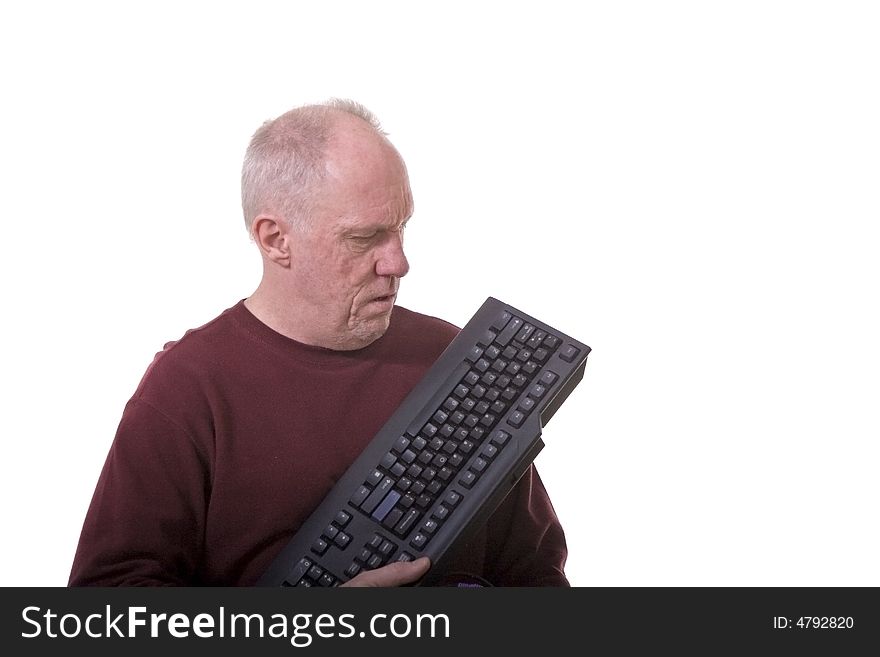 An older man with a computer keyboard looking confused or exasperated. An older man with a computer keyboard looking confused or exasperated