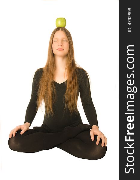 The portrait of a woman in lotus pose with a green apple on her head. The portrait of a woman in lotus pose with a green apple on her head